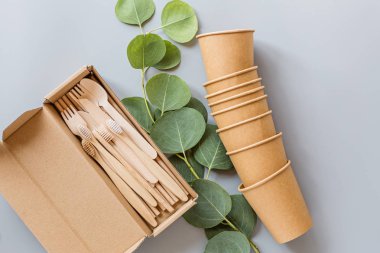 Çevresel doğal kağıt bardaklar, pipetler, tahta çatal bıçaklar gri arka planda yatıyordu. Sürdürülebilir yaşam tarzı kavramı. sıfır atık, plastiksiz eşyalar. Plastik kirliliğini durdurun. Üst görünüm, genel görünüm, şablon, model.