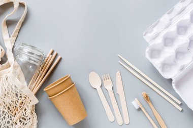 Çevresel doğal kağıt bardaklar, pipetler, torbalar gri arka planda yatıyordu. Sürdürülebilir yaşam tarzı kavramı. sıfır atık, plastiksiz eşyalar. Plastik kirliliğini durdurun. Üst görünüm, genel görünüm, şablon, model.