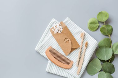 Doğal banyo aksesuarları: ahşap tarak, bambu diş fırçası, masaj fırçası, kulak çubukları, gri kağıtta okaliptüs. Sıfır atık. Model, düz yatak, şablon, üst görünüm, genel giderler