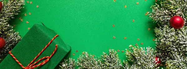 Caja de regalo envuelto navidad y ramas de árbol sobre fondo verde con confeti. concepto de año nuevo. Tarjeta de felicitación, celebración de Navidad 2020. Plano, plantilla, vista superior, espacio para copiar — Foto de Stock