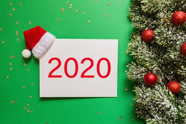 Kırmızı Noel Baba şapkalı boş bir kağıt, yeşil arka planda konfetili noel ağacı dalları. Yeni yıl konsepti. Kutlama kartı, xmas kutlaması 2020. Düz konum, şablon, üst görünüm, kopyalama alanı, modelleme