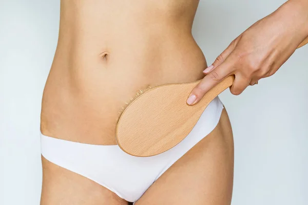 Sexy slim woman's hips and legs wearing white classic underclothes, she using brush for massaging body at home. Cellulite treatment, dry brushing — Stock Photo, Image