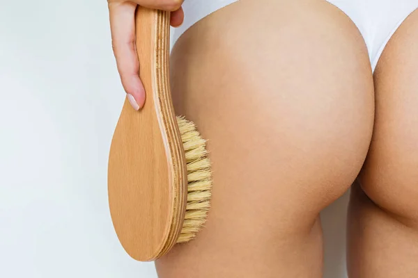 Sexy delgada caderas de la mujer y las piernas con ropa interior clásica blanca, ella usando cepillo para masajear el cuerpo en casa. Tratamiento de celulitis, cepillado en seco — Foto de Stock