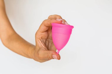 Beyaz arka planda regl bardağı tutan kadın. Dönem boyunca tampon yerine kadın hijyen alternatif ürünü. Adet, kritik günler, kadın dönemleri. Sıfır atık, ekoloji, ekoloji.