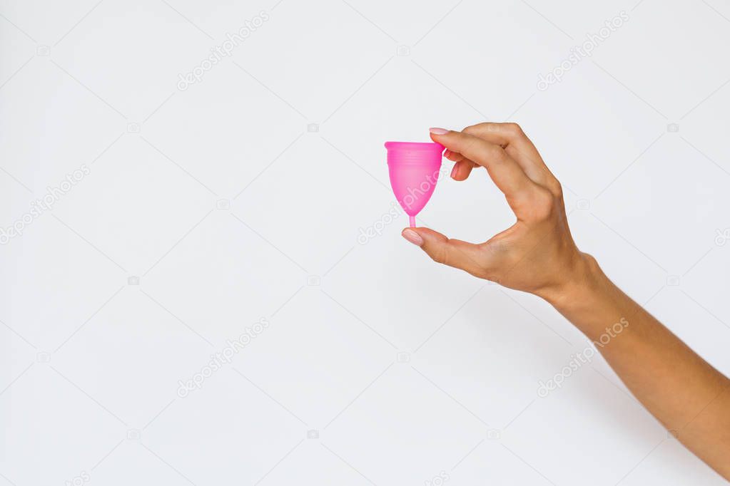 woman holding menstrual cup on white background. Feminine hygiene alternative product instead of tampon during period. Menstruation, critical days, women periods. Zero waste, eco, ecology.