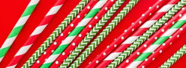 Kırmızı arka planda şeritli içecek pipetleri. Ağ için yatay pankart. Yeni yıl veya yılbaşı şablonu. Minimalizm kavramı. Pop sanat tarzı. Üst manzara, pipetle içme suyu ya da meşrubat içmek için kullanılan düz yer..