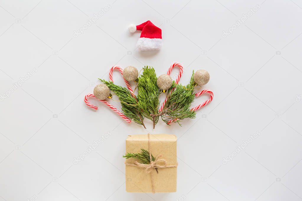 Christmas composition. Wrapped gift, fir branches, lollipop cane on white. new year concept. Greeting card, winter holidays, xmas celebration 2020. Flat lay, top view, copy space, mockup, template