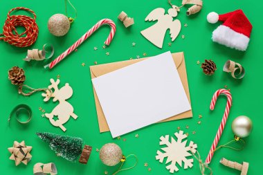 Noel kompozisyonu. Kağıt boş, oyuncaklar yeşil arka planda. Yeni yıl konsepti. Tebrik kartı, kış tatili, kostüm kutlaması 2020. Düz konum, üst görünüm, kopyalama alanı, model, şablon