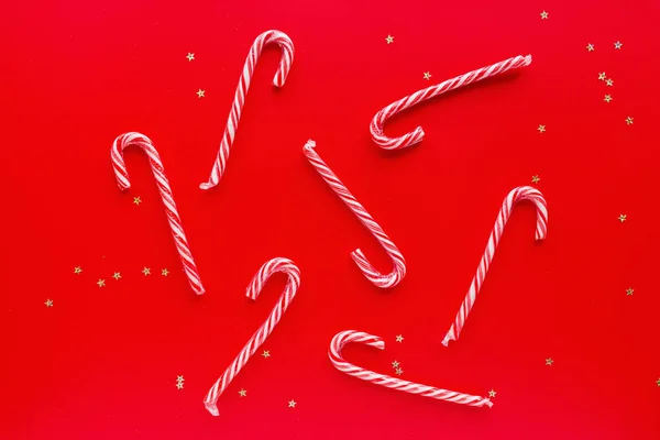 Christmas composition. Candy canes on red paper background. Minimal new year concept. Greeting card, winter holidays, xmas celebration 2020. Flat lay, top view, copy space, mockup, template