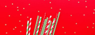 Kırmızı arka planda şeritli içecek pipetleri. Ağ için yatay pankart. Yeni yıl veya yılbaşı şablonu. Minimalizm kavramı. Pop sanat tarzı. Üst manzara, pipetle içme suyu ya da meşrubat içmek için kullanılan düz yer..