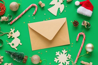 Noel kompozisyonu. Kağıt zarf ve yeşil arka planda oyuncaklar. Yeni yıl konsepti. Tebrik kartı, kış tatili, kostüm kutlaması 2020. Düz konum, üst görünüm, kopyalama alanı, model, şablon