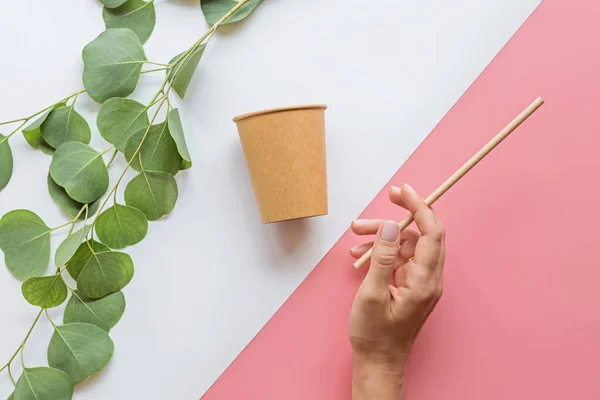 Eco taza de café de papel natural, mano y paja plana yacen sobre fondo blanco y rosa. concepto de estilo de vida sostenible. cero residuos, artículos libres de plástico. detener la contaminación plástica. Vista superior, techo, maqueta — Foto de Stock