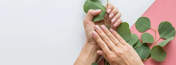 Elegante manicura rosa femenina de moda. Hermosas manos de mujer joven sobre fondo pastel rosa con flores y lugar para el texto. Concepto creativo mínimo. Colocación plana, vista superior, maqueta, espacio para copiar, plantilla — Foto de Stock