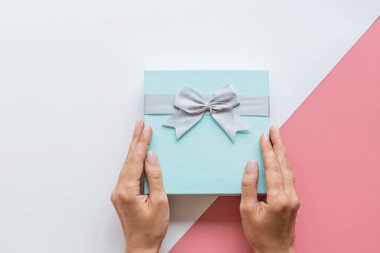Eller hediye kutusunu modern tarzda tutarken soyut bir arkaplan. Xmas geçmişi. Tatil maketi. Noel tebrik kartı. Paket simgesi. İyi ki doğdun Düz yatış, üst görünüm tarzı. Alışveriş satış konsepti