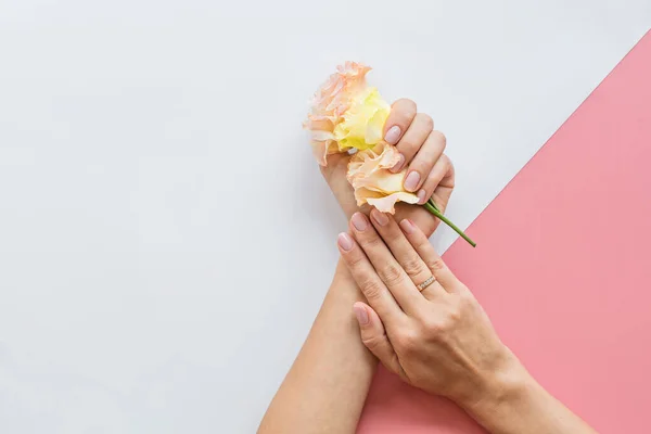 Stijlvolle trendy vrouwelijke roze manicure. Mooie jonge vrouw hand op roze en witte achtergrond met bloemen en plaats voor tekst. Minimaal creatief concept. Platte lay, bovenaanzicht, maquette, kopieer ruimte template — Stockfoto