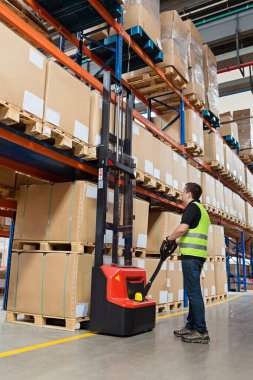 Modern otomatik depoda forklift üzerinde çalışan üniformalı bir depo çalışanı. Kutular deponun raflarında. Depo, makine konsepti. Stokta lojistik.