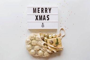 Tatil çerçevesi yeniden kullanılabilir sicim torbasında noel topları ve şık beyaz masa manzarasında konfeti. Moda geçmişi. Düz yatıyordu. Parti maketi. xmas 2020 kutlaması, yeni yıl konsepti, şablon
