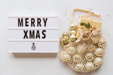 Tatil çerçevesi yeniden kullanılabilir sicim torbasında noel topları ve şık beyaz masa manzarasında konfeti. Moda geçmişi. Düz yatıyordu. Parti maketi. xmas 2020 kutlaması, yeni yıl konsepti, şablon