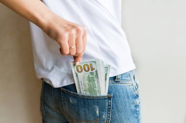 Kadının nakit parası var. Zenginlik ve refah kavramı. Kolay ve hızlı bir şekilde nakit para al. 100 dolarlık banknotlar kotun arka cebinde. Finansal bankacılık, alışveriş, iş konsepti