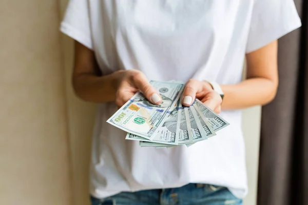 Bizneswoman dostała gotówkę. Bogactwo i dobre samopoczucie. Kobiece ręce trzymające studolarówki. Kobieta w białej koszuli trzyma stos banknotów dolarowych na beżowym tle. Łatwe pożyczki gotówkowe. — Zdjęcie stockowe