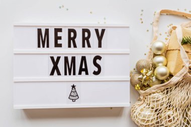 Tatil çerçevesi yeniden kullanılabilir sicim torbasında noel topları ve şık beyaz masa manzarasında konfeti. Moda geçmişi. Düz yatıyordu. Parti maketi. xmas 2020 kutlaması, yeni yıl konsepti, şablon