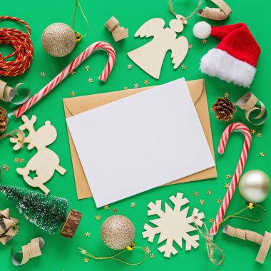Noel kompozisyonu. Kağıt boş, oyuncaklar yeşil arka planda. Yeni yıl konsepti. Tebrik kartı, kış tatili, kostüm kutlaması 2020. Düz konum, üst görünüm, kopyalama alanı, model, şablon