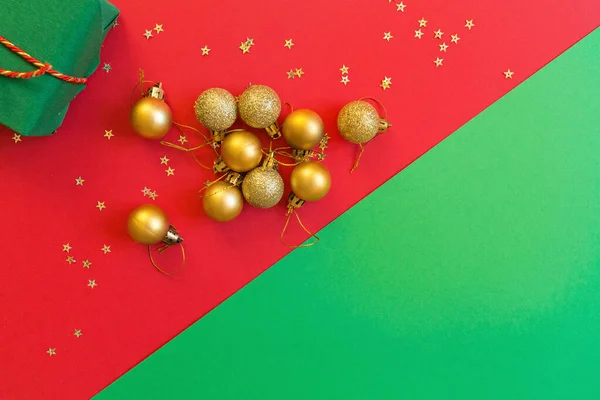 Різдвяна композиція. Зелена подарункова коробка, золоті іграшки на червоно-зеленому тлі з золотим конфетті. концепція нового року. Вітальна листівка, святкування Різдва 2020 року. Плоский простір, вид зверху, простір для копіювання, макет — стокове фото