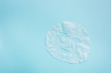 Pastel mavi kağıt arka plan üzerine levha yüz maskesi. Cilt bakımı, dermatoloji, güzellik konsepti. Üst görünüm, düz döşeme, mockup, genel merkez, kopyalama alanı, şablon