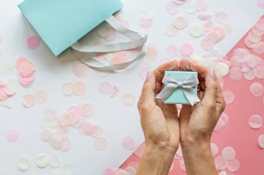 Hediye ya da hediye kutusu, eller ve konfeti pembe masanın üstünde. Doğum günü, Anneler Günü, 8 Mart, Noel, Yeni Yıl, Sevgililer Günü ya da düğün için beste. Tatil kavramı