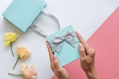 Hediye kutusu ya da hediye kutusu ve eller pembe masanın üstünde. Doğum günü, Anneler Günü, 8 Mart, Noel, Yeni Yıl, Sevgililer Günü ya da düğün için beste. Tatil kavramı