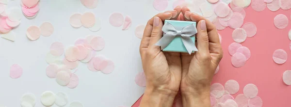선물 상자, 선물 상자, 손, 그리고 콘 페티가 분홍색 테이블 위에 있습니다. 웹 배너. 편평 한 꽃꽂이는 생일, 어머니 날, 3 월 8 일, 크리스마스, 새해, 발렌타인데이, 결혼식을 위한 것이다. 축일 개념 — 스톡 사진