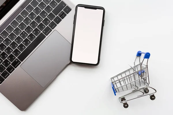 Creative promotion composition for Black Friday sale on white background, next laptop, grocery cart, mobile phone. Плоская кладка, вид сверху, накладные расходы, макет, искушение — стоковое фото