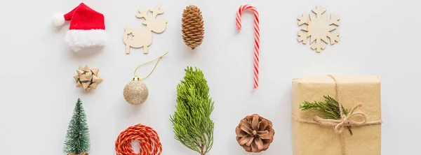 Різдвяний загорнутий подарунок, дерев'яні іграшки, льодяна тростина на білому. концепція нового року. Горизонтальний банер для Інтернету. Вітальна листівка, святкування Різдва 2020 року. Плоский простір, вид зверху, простір для копіювання, макет, шаблон — стокове фото