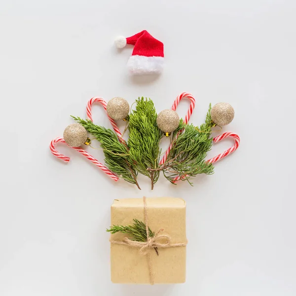 Vánoční kompozice. Zabalený dárek, jedlové větve, lízátková hůl na bílém. novoroční koncept. Pozdrav, zimní prázdniny, vánoční oslavy2020. Byt ležel, horní pohled, kopírovací prostor, mockup, šablona — Stock fotografie