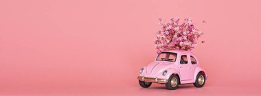 Pembe retro oyuncak araba pembe arka planda bir buket çiçek getiriyor. Sevgililer Günü, 14 Şubat kartı. Uluslararası Kadınlar Günü 8 Mart, Anneler Günü, Doğum günü hediyesi. Boşluğu kopyala, düzenle, şablonu en aza indir