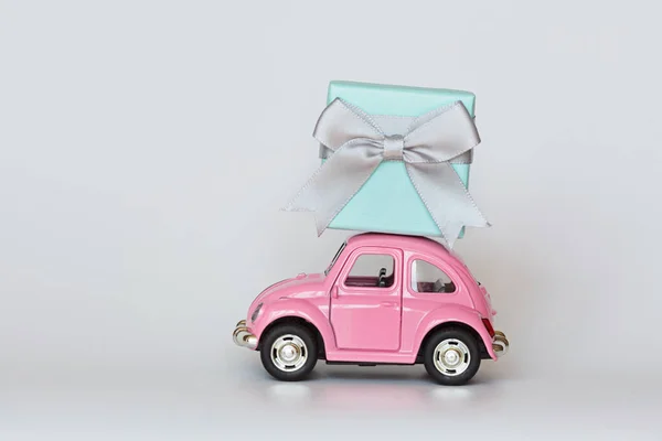 분홍색 역 장난감 자동차가 흰색 지붕 위에 선물 상자를 배달합니다. 2 월 14 일 발렌타인데이, 국제 여성의 날 3 월 8 일, 어머니 날, 생일 축하. 복사 공간, 흉내, 주형, 최소화 — 스톡 사진