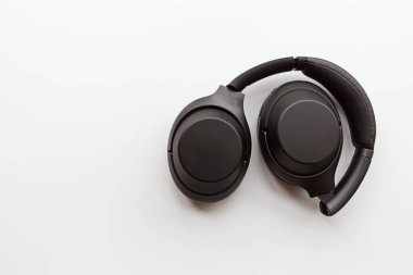 Beyaz arka planda siyah modern kablosuz kulaklıklar. Teknoloji konsepti, minimal düz yatış stili, model, şablon, üst görünüm, genel giderler