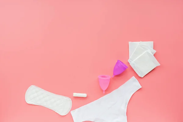 Ceașcă menstruală cu sac, tampoane igienice, tampoane, chiloți albi pe fundal roz. Produsul alternativ de igienă feminină în timpul perioadei. Conceptul de sănătate pentru femei . — Fotografie, imagine de stoc