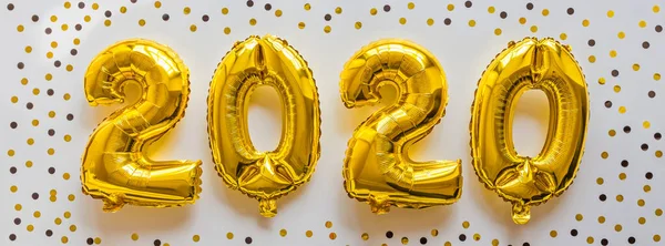 Foil balloons golden color in the form of numbers 2020. New year celebration, christmas, xmas. Flat lay with Air Balloons, top view, mockup, overhead, minimal style. Holiday party decoration.