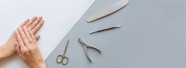 Modaya uygun pembe kadın manikürü. Güzel, genç bir kadın elleri gri arkaplanda, çiçek ve yazı için yer var. Asgari yaratıcı konsept. Düz konum, üst görünüm, maket, boşluk kopyala, şablon