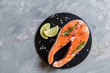 Koyu taş arka plan üzerinde baharat ile taze çiğ somon balık biftek. Balık, üst görünüm, düz yatıyordu, mockup, havai yapılmış Yaratıcı düzeni. Sağlıklı gıda kavramı