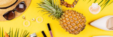 Kadın moda kıyafeti ile yaz kompozisyonu. Taze ananas, şapka, tropikal palmiye yaprakları, hasır şapka, bambu çanta, sarı arka planda ayakkabılar. Düz konum, üst görünüm, genel görünüm, model, şablon, boşluk kopyala