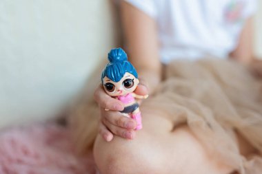 Changxing, Çin - 18 Haziran 2020. Küçük kız bale elbisesi içinde yatak odasında oturuyor ve Coronavirus covid-10 karantinası sırasında lol bebekleriyle oynuyor. Pandemik tecrit sırasında evde kal