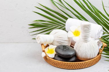 Spa masajı, vücut bakımı geçmişi. Gri beton masada spa poşetleri, havlu ve tropikal çiçekler. kopyalama alanı. Güzellik ve sağlık hizmetleri kavramı