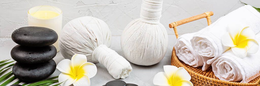 Spa massage Aromatherapy body care background. Spa herbal balls, cosmetics, towel and tropical leaves on gray concrete table. Web banner. Beauty and health care concept