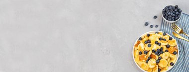Gri beton arka planda küçük krepler ve yaban mersinli moda ev kahvaltısı. Web afişi. Düz konum, üst görünüm, genel görünüm, model, şablon, kopyalama alanı. Yukarıdan görüntüle