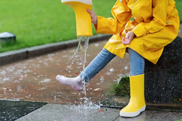 穿着黄色雨衣和橡胶靴的可爱小女孩在雨中走在户外 坏天气 夏天的热带风暴 秋天的流行观念 高质量的照片 — 图库照片