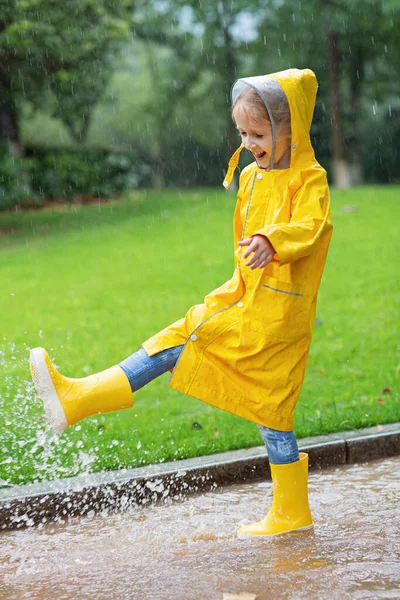 穿着黄色雨衣和橡胶靴的可爱小女孩在雨中走在户外 坏天气 夏天的热带风暴 秋天的流行观念 高质量的照片 — 图库照片