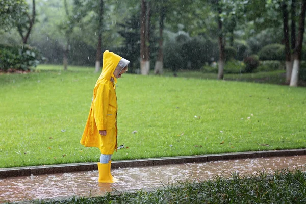 穿着黄色雨衣和橡胶靴的可爱小女孩在雨中走在户外 坏天气 夏天的热带风暴 秋天的流行观念 高质量的照片 — 图库照片