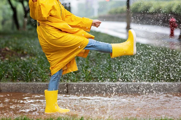 穿着黄色雨衣和橡胶靴的可爱小女孩在雨中走在户外 坏天气 夏天的热带风暴 秋天的流行观念 高质量的照片 — 图库照片